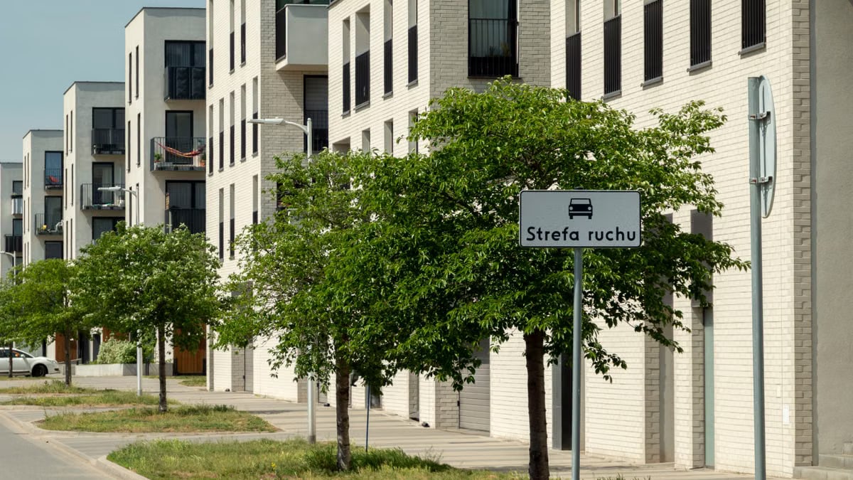 Contemporary apartment buildings with green trees on a sunny street in Wrocław, Poland.